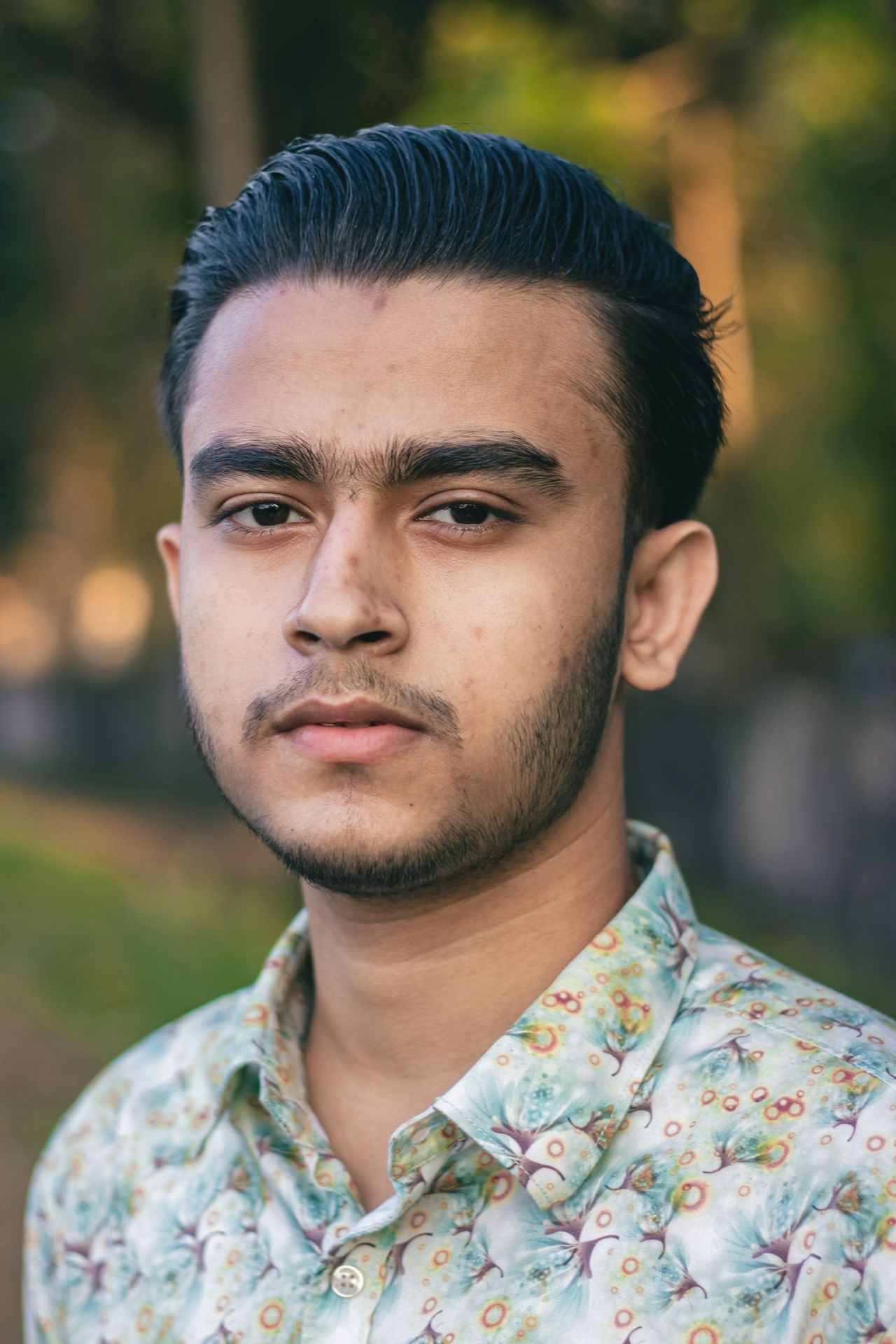 a man with a flowered shirt looking at the camera